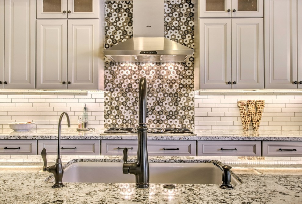 Mid-sized eclectic porcelain tile and brown floor eat-in kitchen photo in Phoenix with an undermount sink, raised-panel cabinets, white cabinets, granite countertops, white backsplash, ceramic backsplash, stainless steel appliances, an island and white countertops