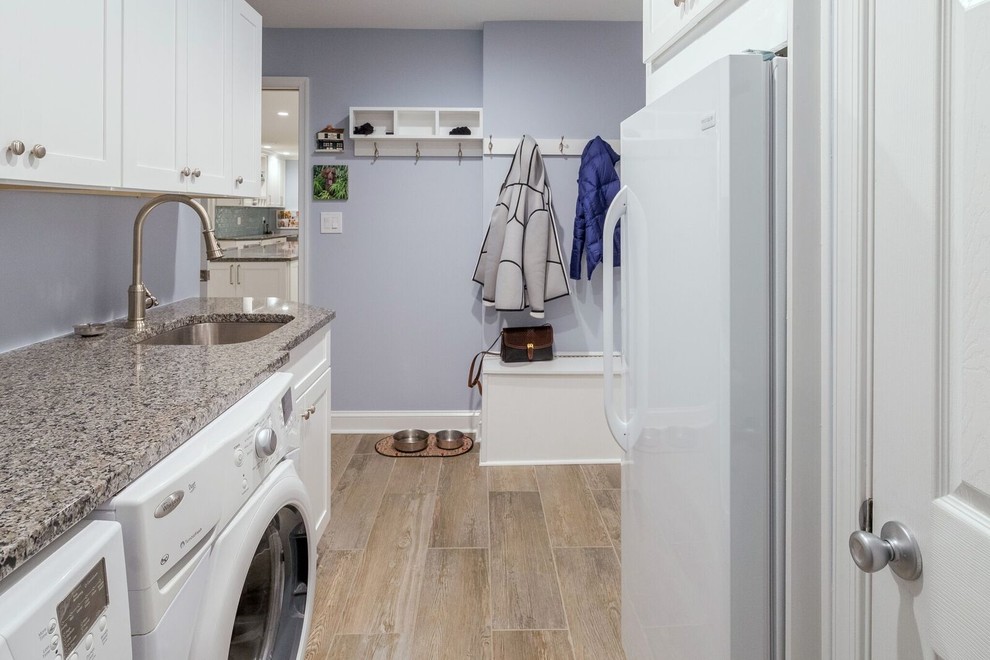 This is an example of a mid-sized transitional utility room in Orange County with an undermount sink, shaker cabinets, white cabinets, granite benchtops, porcelain floors, a side-by-side washer and dryer, grey benchtop and blue walls.