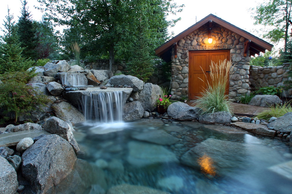 Photo of a large country backyard full sun garden in Seattle with natural stone pavers and with waterfall.