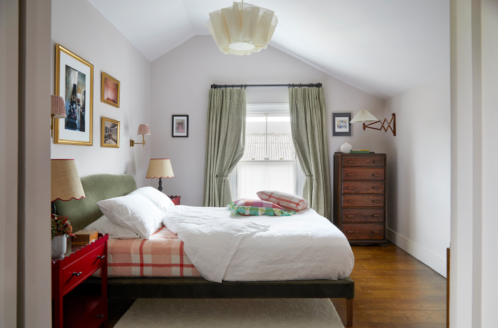 This is an example of a traditional bedroom in London with white walls, dark hardwood flooring, brown floors and a vaulted ceiling.