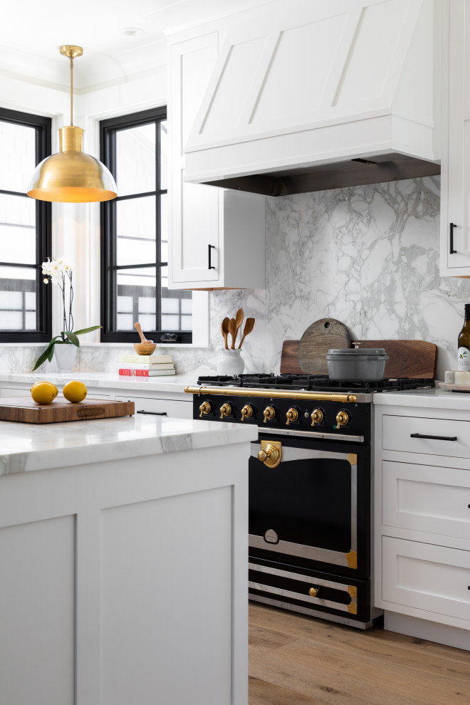 Eat-in kitchen - mid-sized coastal l-shaped medium tone wood floor and beige floor eat-in kitchen idea in Other with a farmhouse sink, recessed-panel cabinets, white cabinets, marble countertops, white backsplash, marble backsplash, paneled appliances, a peninsula and white countertops
