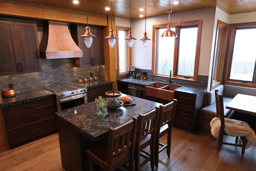 Idéer för ett rustikt svart kök med öppen planlösning, med en rustik diskho, skåp i shakerstil, skåp i mellenmörkt trä, bänkskiva i kvartsit, svart stänkskydd, stänkskydd i skiffer, rostfria vitvaror, mellanmörkt trägolv, en köksö och brunt golv