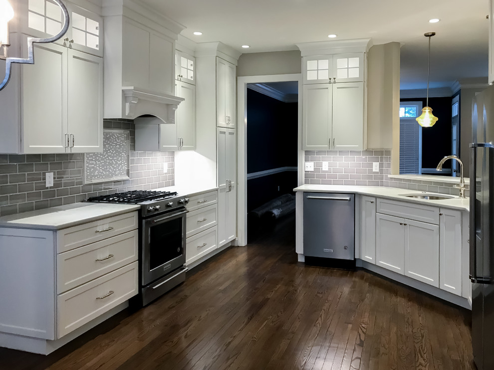Design ideas for a mid-sized contemporary u-shaped separate kitchen in Wilmington with an undermount sink, shaker cabinets, white cabinets, quartzite benchtops, grey splashback, subway tile splashback, stainless steel appliances, dark hardwood floors, no island, brown floor and white benchtop.