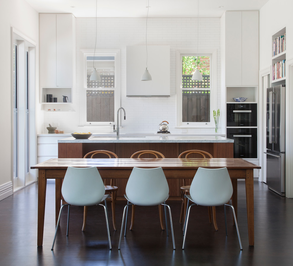 Design ideas for a mid-sized contemporary u-shaped eat-in kitchen in Melbourne with an undermount sink, flat-panel cabinets, marble benchtops, white splashback, ceramic splashback, black appliances, dark hardwood floors, with island and white cabinets.
