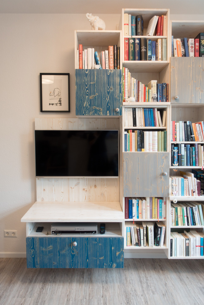 Imagen de sala de estar con biblioteca abierta marinera pequeña con paredes beige, suelo vinílico, televisor colgado en la pared y suelo marrón