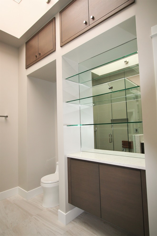 Photo of a mid-sized contemporary master bathroom in Other with flat-panel cabinets, medium wood cabinets, a corner shower, a one-piece toilet, an undermount sink, marble benchtops and a hinged shower door.
