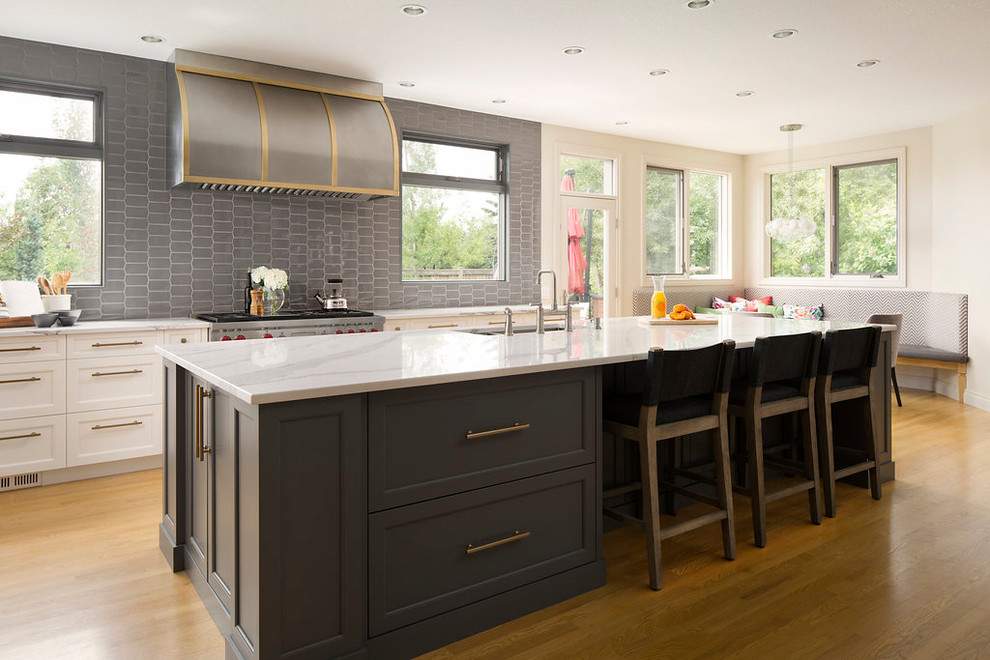 Open concept kitchen - large transitional single-wall light wood floor and brown floor open concept kitchen idea in Calgary with an undermount sink, shaker cabinets, white cabinets, marble countertops, gray backsplash, ceramic backsplash, stainless steel appliances and an island