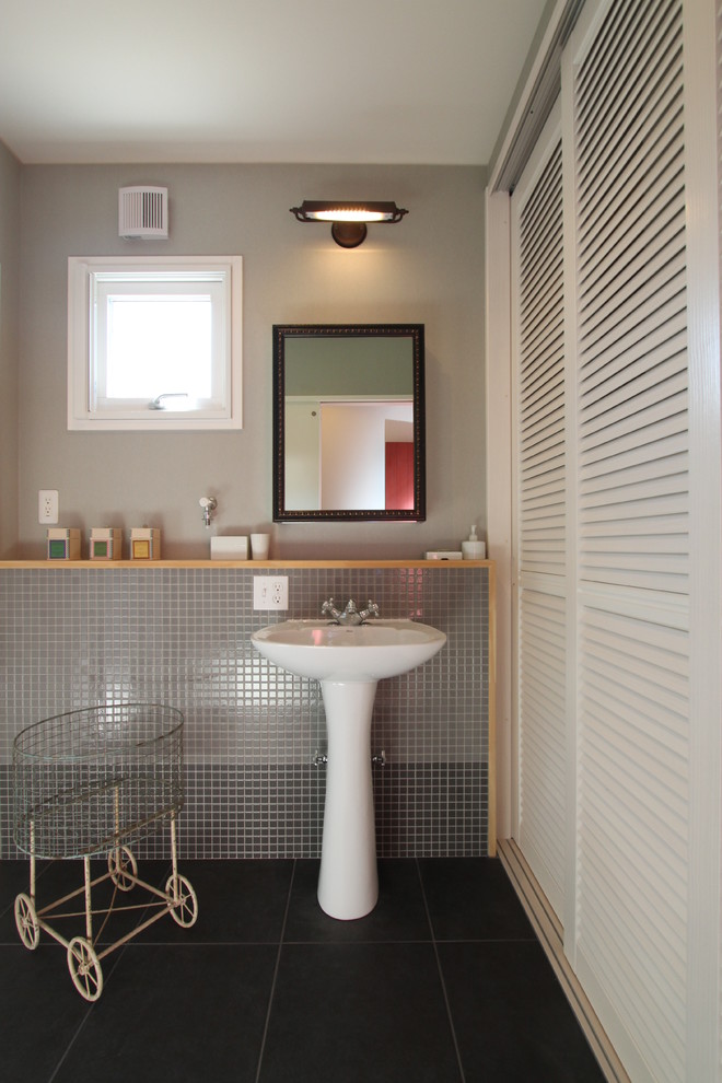 Contemporary powder room in Other with louvered cabinets, white cabinets, gray tile, mosaic tile, grey walls, cement tiles, a pedestal sink and black floor.