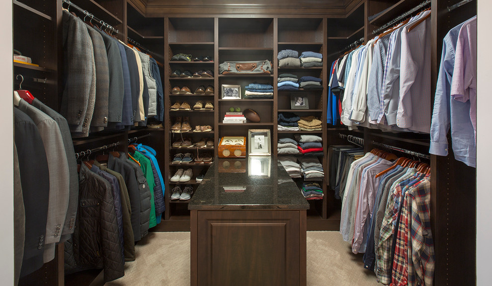 Traditional men's walk-in wardrobe in Omaha with raised-panel cabinets, dark wood cabinets and carpet.