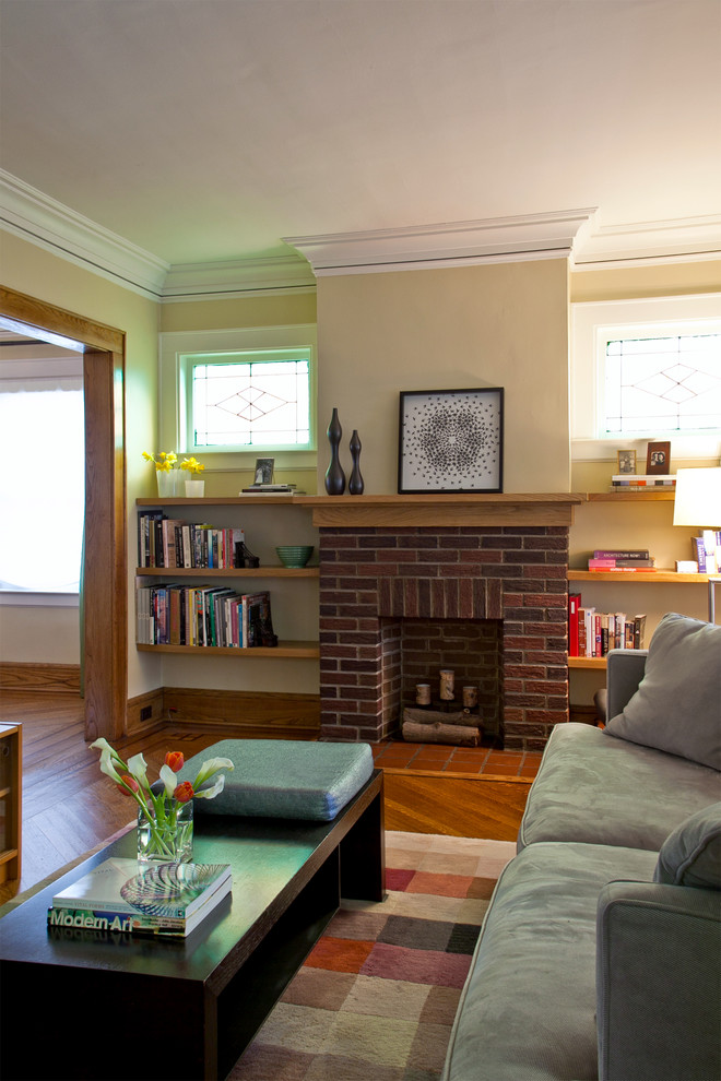 This is an example of a mid-sized transitional living room in New York with yellow walls, medium hardwood floors, a standard fireplace and a brick fireplace surround.