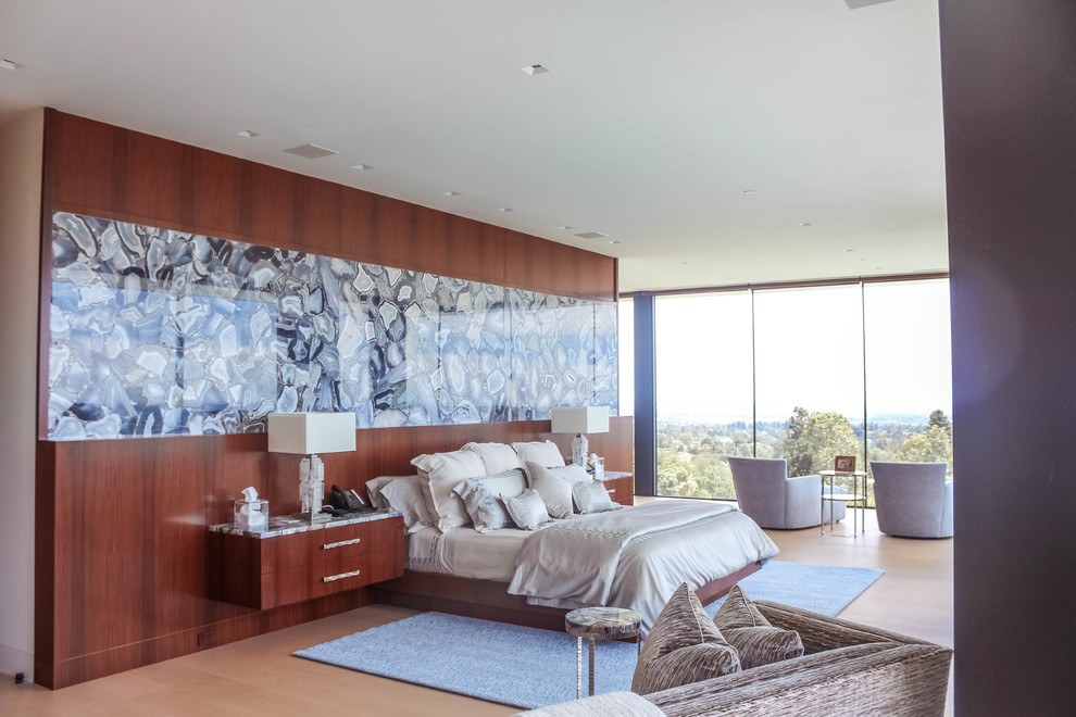 This is an example of a large modern master bedroom in Los Angeles with beige walls, light hardwood floors, a ribbon fireplace, a stone fireplace surround and white floor.