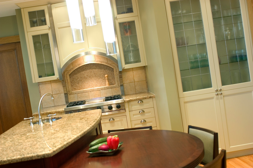 Example of a large transitional l-shaped porcelain tile and beige floor enclosed kitchen design with an undermount sink, shaker cabinets, granite countertops, beige backsplash, mosaic tile backsplash, stainless steel appliances, an island and beige countertops