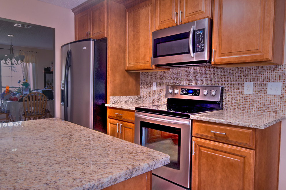 Inspiration for a mid-sized l-shaped cement tile floor eat-in kitchen remodel with an undermount sink, raised-panel cabinets, medium tone wood cabinets, granite countertops, brown backsplash, mosaic tile backsplash, stainless steel appliances, an island and brown countertops
