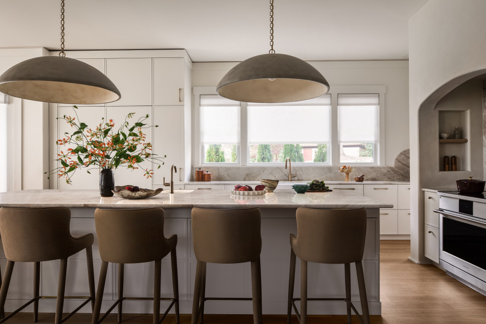 Inspiration for a transitional l-shaped medium tone wood floor and brown floor kitchen remodel in DC Metro with a farmhouse sink, shaker cabinets, white cabinets, gray backsplash, stone slab backsplash, stainless steel appliances, an island and gray countertops