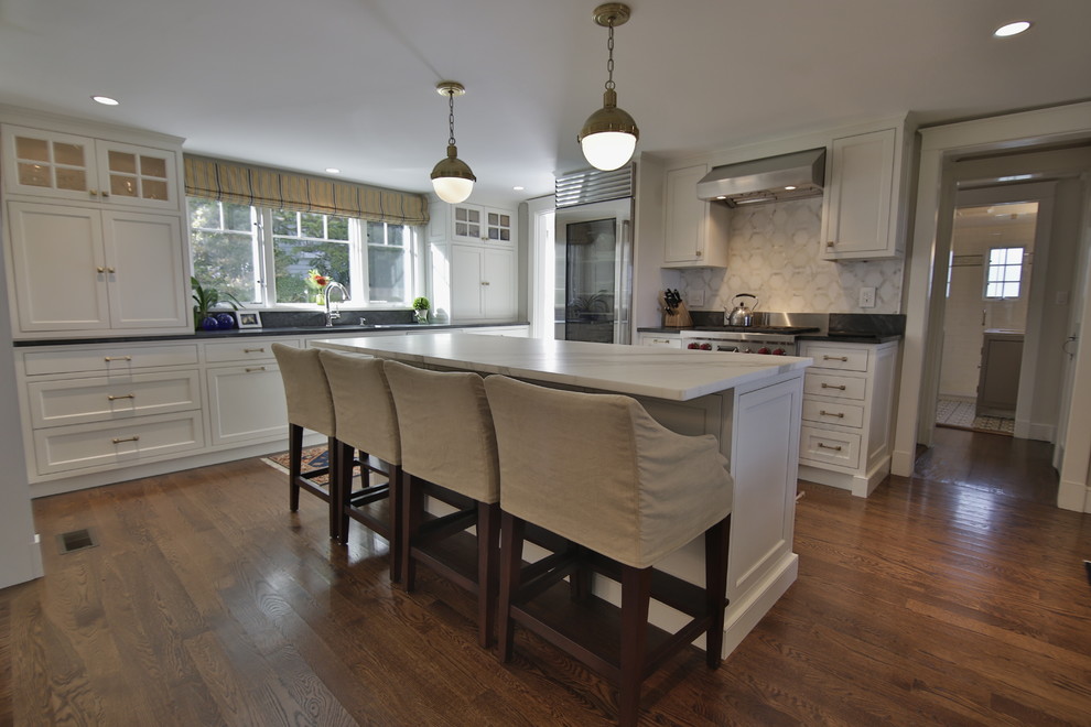This is an example of a large traditional l-shaped open plan kitchen in Boston with an undermount sink, beaded inset cabinets, white cabinets, marble benchtops, white splashback, stone tile splashback, stainless steel appliances, medium hardwood floors, with island, brown floor and white benchtop.