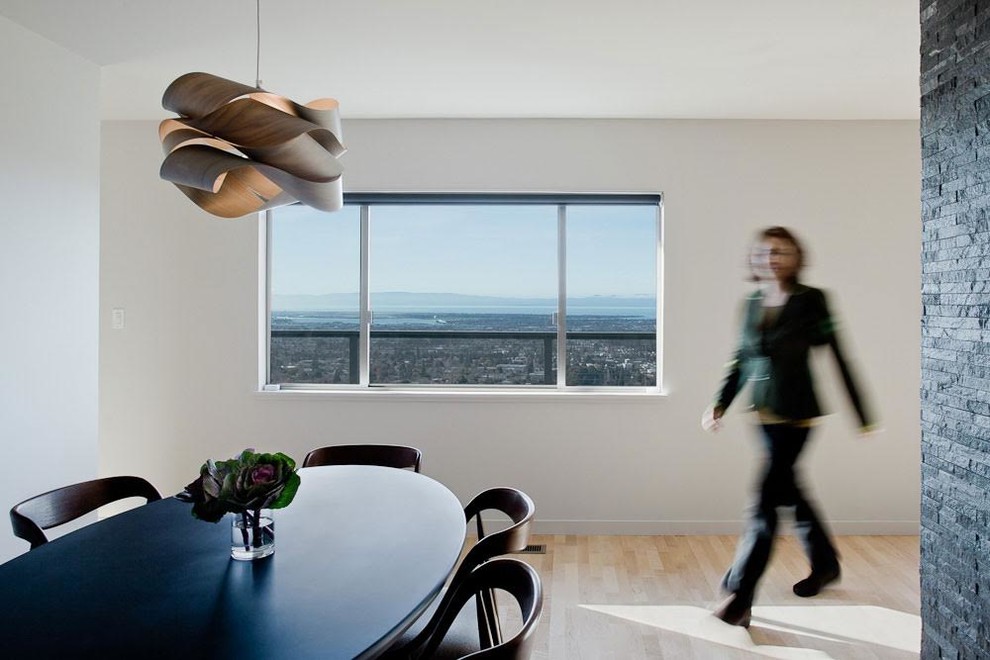 Photo of a modern dining room in San Francisco with white walls and light hardwood floors.