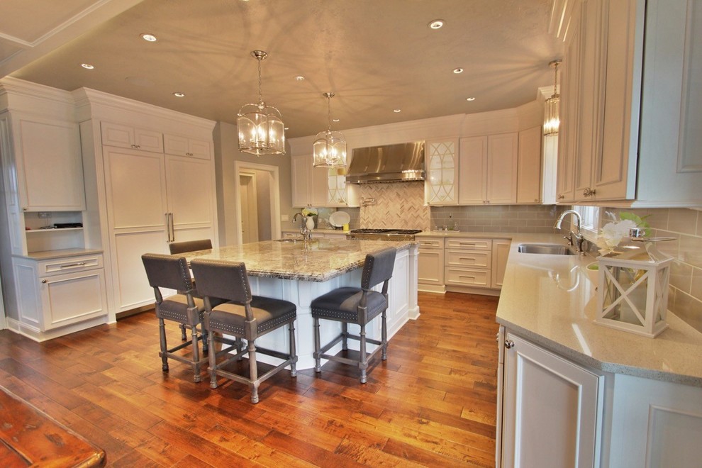 Inspiration for a large l-shaped medium tone wood floor eat-in kitchen remodel with a double-bowl sink, white cabinets, granite countertops, gray backsplash, glass tile backsplash, stainless steel appliances and an island