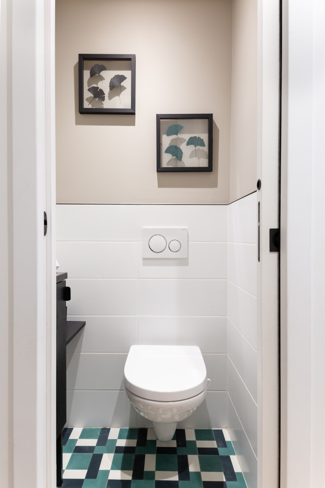 Réalisation d'un WC suspendu minimaliste de taille moyenne avec un placard à porte plane, des portes de placard noires, un carrelage blanc, des carreaux de céramique, un mur beige, un sol en carrelage de céramique, un sol multicolore, un plan de toilette noir, meuble-lavabo suspendu et un lavabo suspendu.