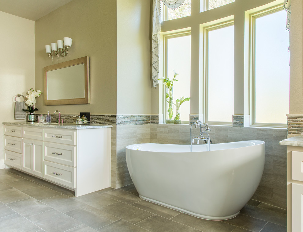 Photo of a mid-sized transitional master bathroom in Other with shaker cabinets, white cabinets, a freestanding tub, a one-piece toilet, beige tile, mosaic tile, beige walls, porcelain floors, an undermount sink, granite benchtops, blue floor, beige benchtops, a single vanity and a built-in vanity.