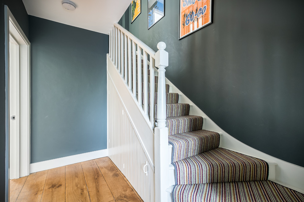 Design ideas for a mid-sized contemporary carpeted staircase in London with wood risers and wood railing.