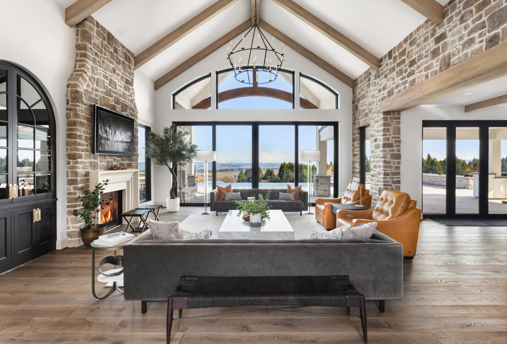 Inspiration for an expansive open plan living room in Portland with white walls, medium hardwood flooring, a standard fireplace, a brick fireplace surround, a wall mounted tv and exposed beams.