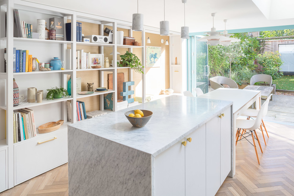 Inspiration for a contemporary single-wall eat-in kitchen in London with a drop-in sink, flat-panel cabinets, white cabinets, marble benchtops, marble splashback, medium hardwood floors, with island and brown floor.