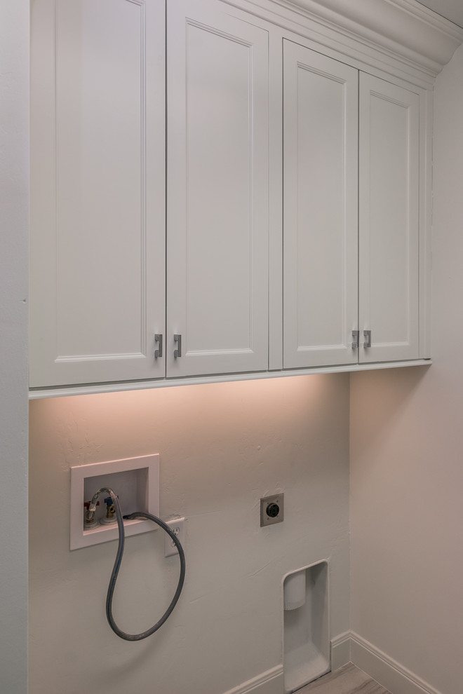 Example of a mid-sized transitional galley medium tone wood floor and brown floor home design design in Austin with an undermount sink, shaker cabinets, white cabinets, marble countertops, white walls and a side-by-side washer/dryer