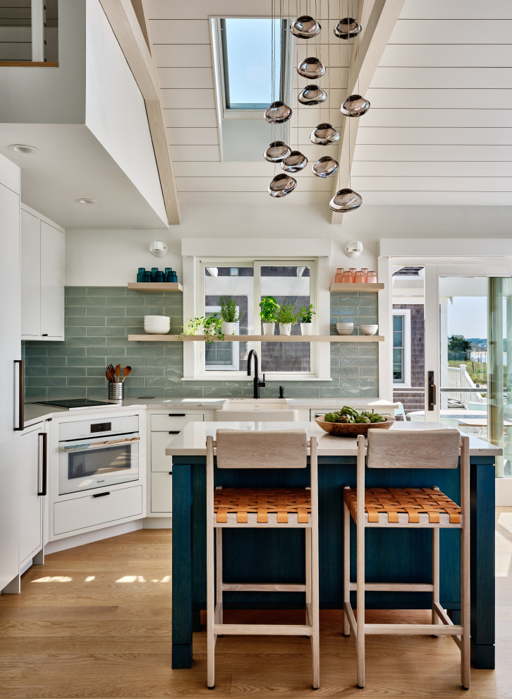 Small beach style l-shaped eat-in kitchen in Boston with a farmhouse sink, open cabinets, white cabinets, quartz benchtops, green splashback, porcelain splashback, panelled appliances, light hardwood floors, with island, beige floor, white benchtop and exposed beam.