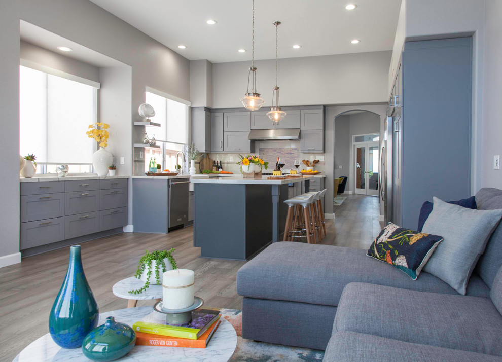 Eat-in kitchen - large transitional l-shaped medium tone wood floor and brown floor eat-in kitchen idea with a farmhouse sink, shaker cabinets, gray cabinets, quartzite countertops, multicolored backsplash, glass tile backsplash, stainless steel appliances, an island and white countertops