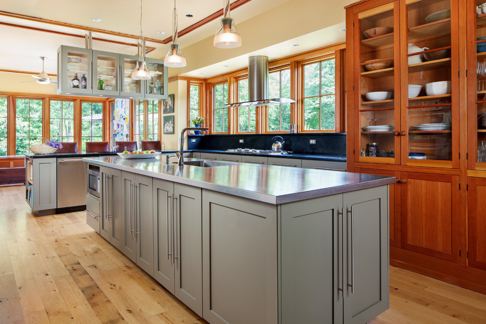 Photo of an arts and crafts l-shaped kitchen in Wilmington with an integrated sink, glass-front cabinets, medium wood cabinets, medium hardwood floors and with island.
