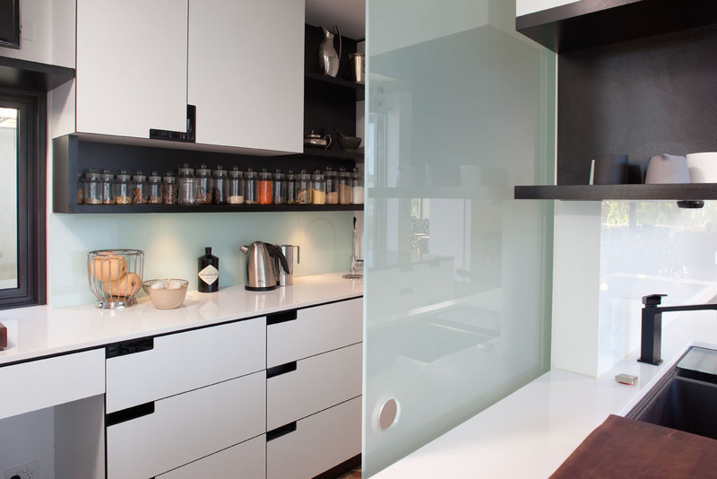 Design ideas for a modern galley kitchen pantry in Perth with a drop-in sink, flat-panel cabinets, white cabinets, granite benchtops, white splashback, glass sheet splashback, black appliances and with island.