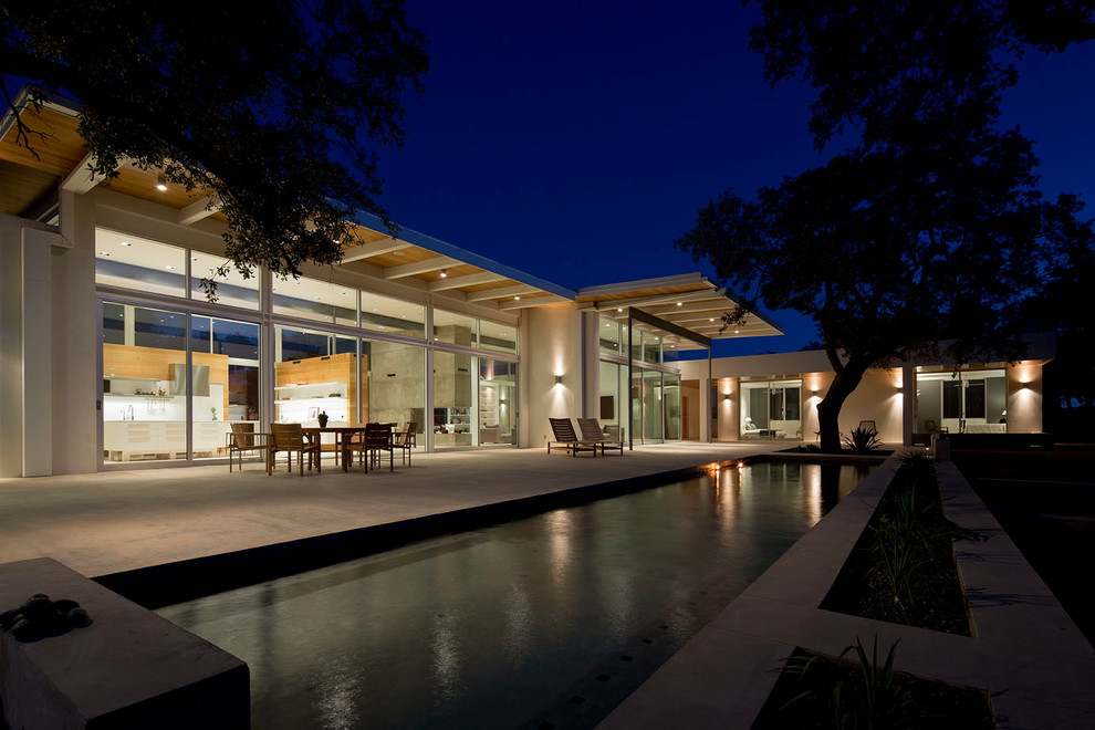 Design ideas for a large contemporary backyard rectangular pool in Austin with concrete slab.