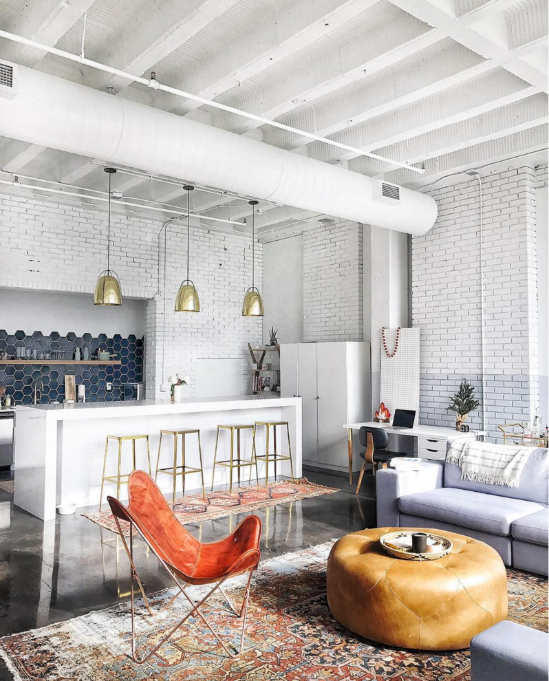 This is an example of a large industrial open concept living room in San Francisco with white walls and concrete floors.