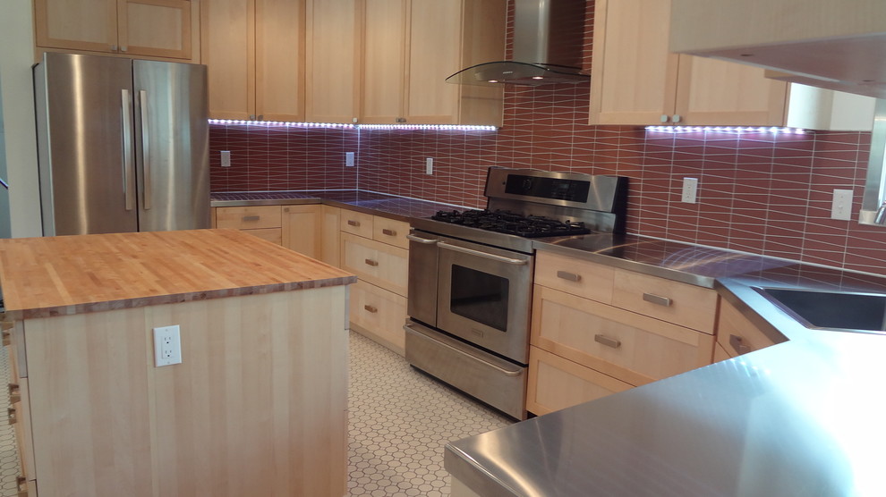 Contemporary kitchen in Albuquerque with a drop-in sink, raised-panel cabinets, light wood cabinets, stainless steel benchtops, red splashback, ceramic splashback, stainless steel appliances, ceramic floors and multiple islands.