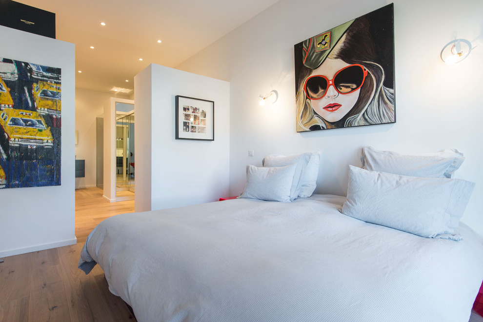 This is an example of a contemporary bedroom in Other with white walls and medium hardwood floors.