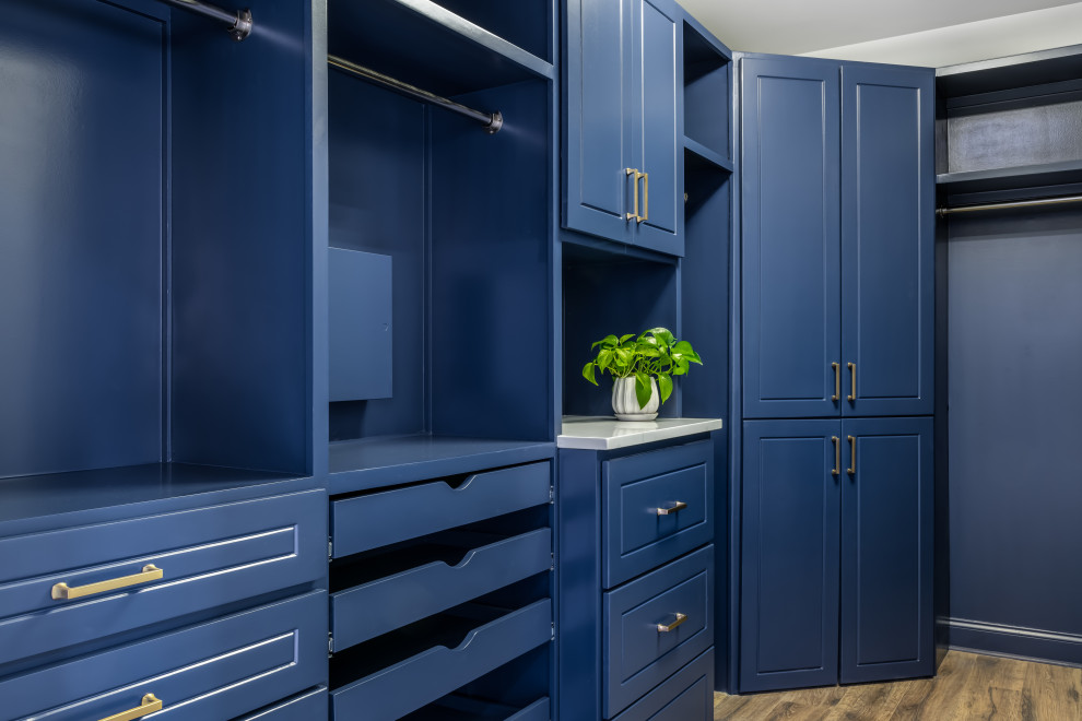 This is an example of a large transitional gender-neutral storage and wardrobe in Atlanta with raised-panel cabinets, blue cabinets, vinyl floors and brown floor.