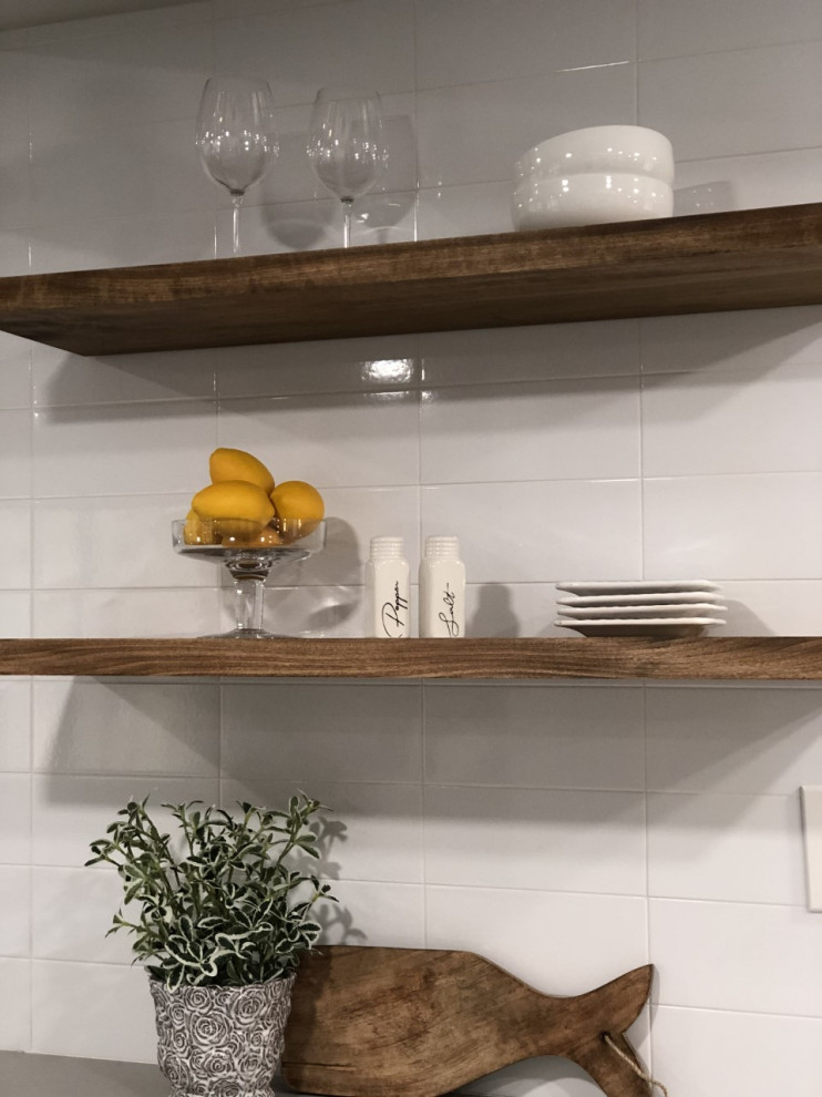 Cette image montre une cuisine américaine minimaliste avec un placard sans porte, un plan de travail en quartz, une crédence blanche, une crédence en carrelage métro et un plan de travail gris.