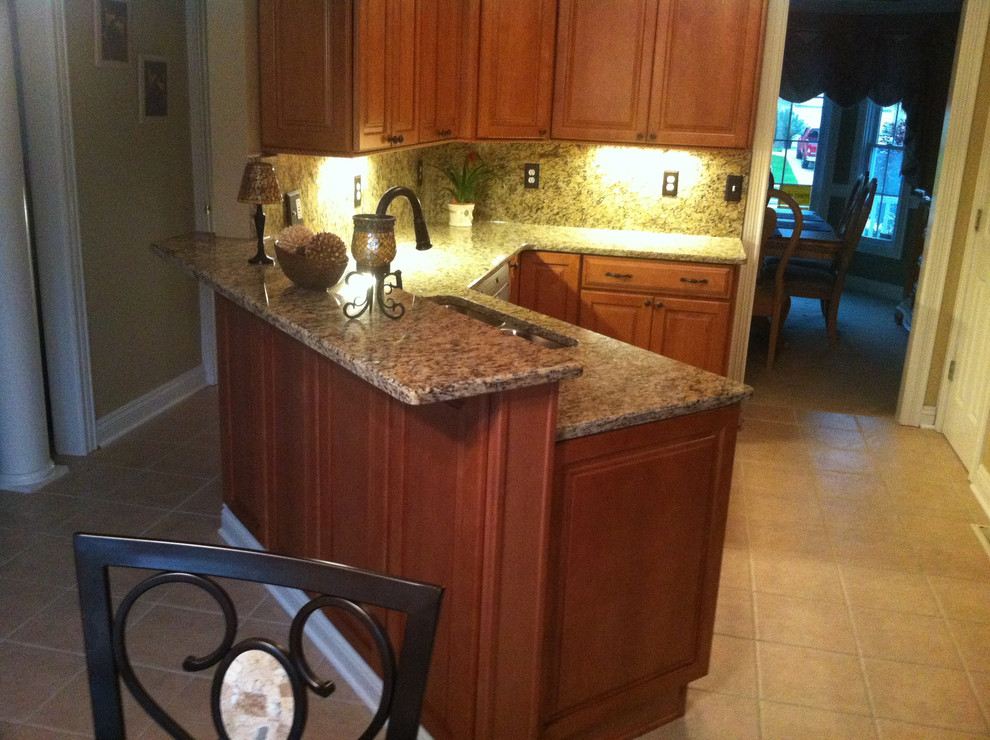 Example of a small classic u-shaped porcelain tile eat-in kitchen design in Cleveland with an undermount sink, raised-panel cabinets, medium tone wood cabinets and granite countertops
