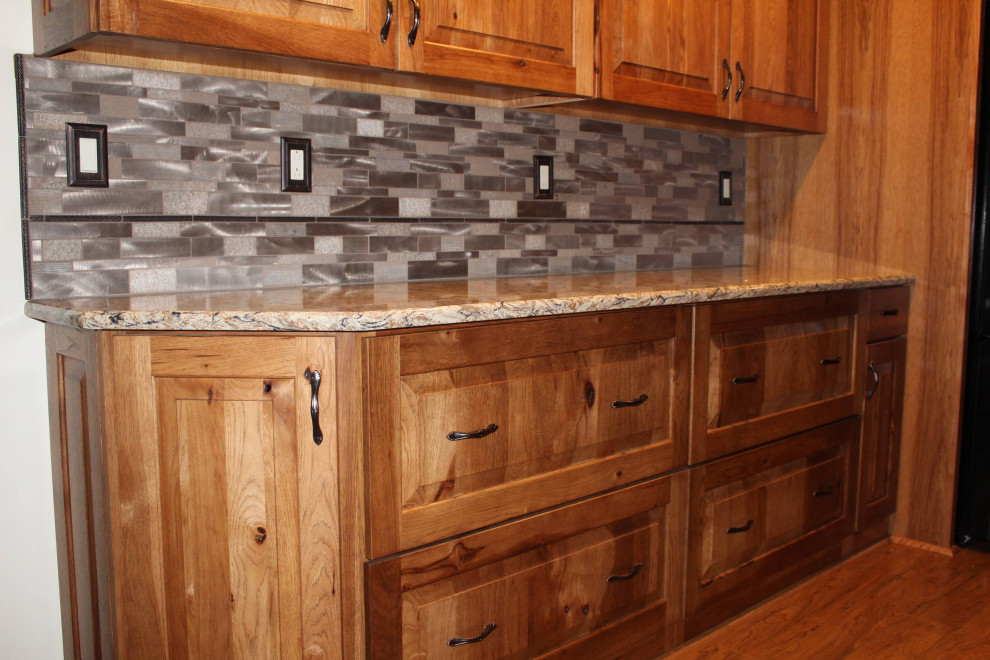 Inspiration for a large rustic l-shaped medium tone wood floor and brown floor open concept kitchen remodel with an undermount sink, raised-panel cabinets, quartzite countertops, metallic backsplash, black appliances, an island, brown countertops and medium tone wood cabinets