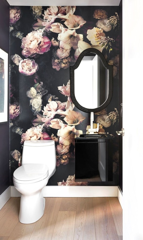 Design ideas for a small traditional powder room in Toronto with flat-panel cabinets, black cabinets, a one-piece toilet, black walls, light hardwood floors and an integrated sink.
