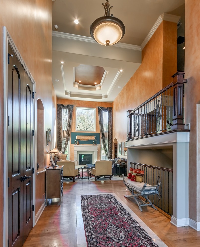 Foyer - huge transitional medium tone wood floor foyer idea in Omaha with orange walls and a medium wood front door