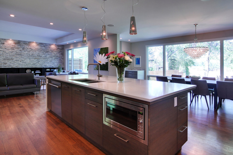 Inspiration for a transitional medium tone wood floor and brown floor kitchen remodel in Calgary with an undermount sink, flat-panel cabinets, quartz countertops, gray backsplash, marble backsplash, stainless steel appliances and an island