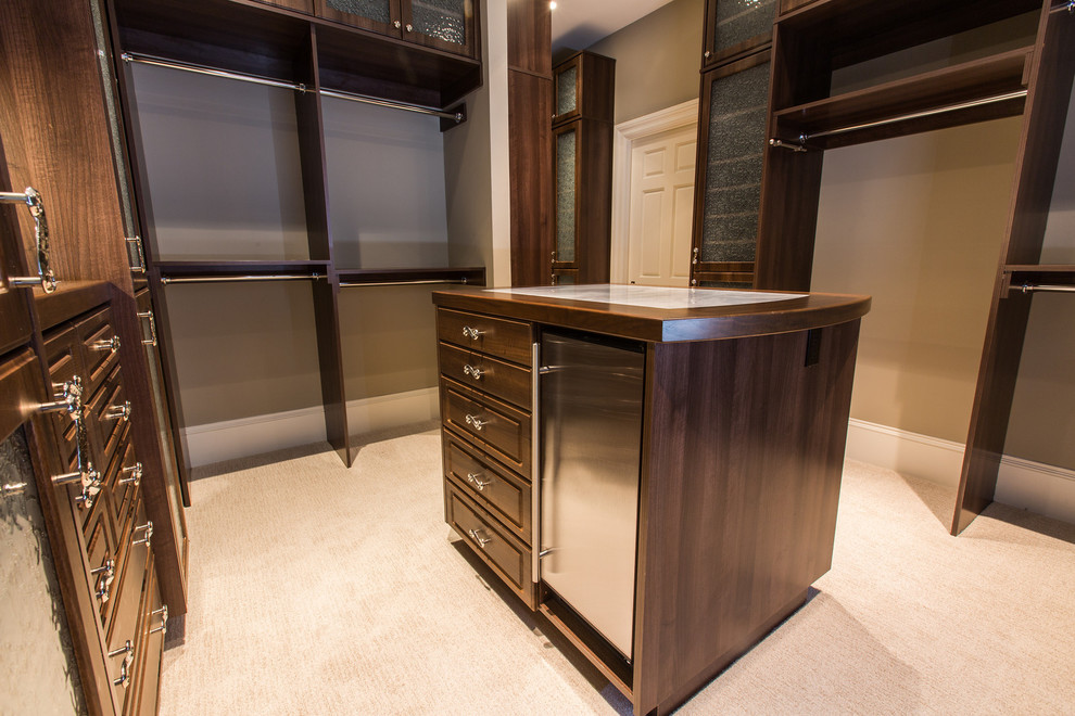 Photo of an expansive traditional women's walk-in wardrobe in San Diego with raised-panel cabinets, dark wood cabinets and carpet.