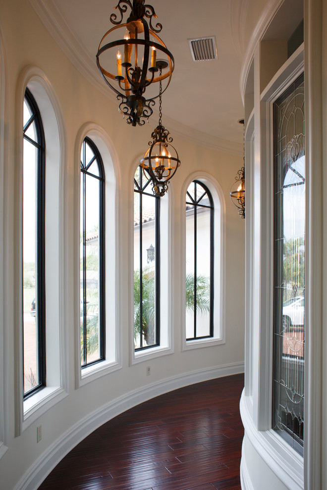 This is an example of a mid-sized mediterranean hallway in Jacksonville with white walls, dark hardwood floors and red floor.