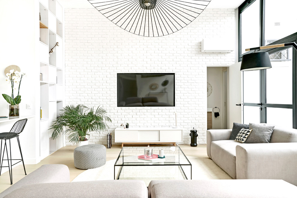This is an example of a scandinavian open concept family room in Paris with white walls, light hardwood floors, no fireplace and a wall-mounted tv.
