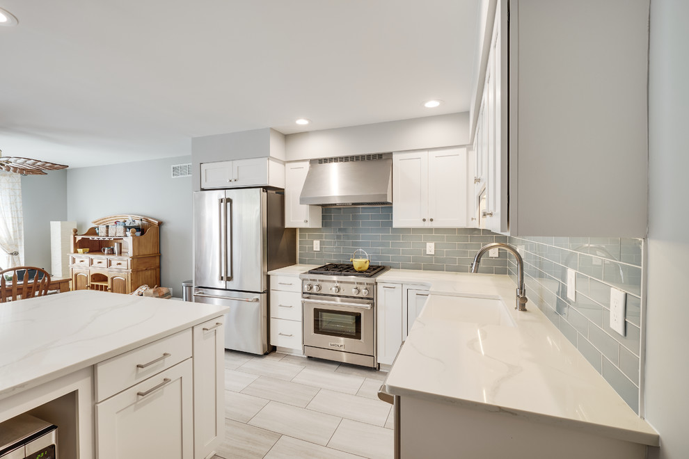 Inspiration for a small modern l-shaped separate kitchen in Philadelphia with a farmhouse sink, recessed-panel cabinets, white cabinets, quartz benchtops, blue splashback, glass tile splashback, stainless steel appliances, vinyl floors, with island, beige floor and white benchtop.