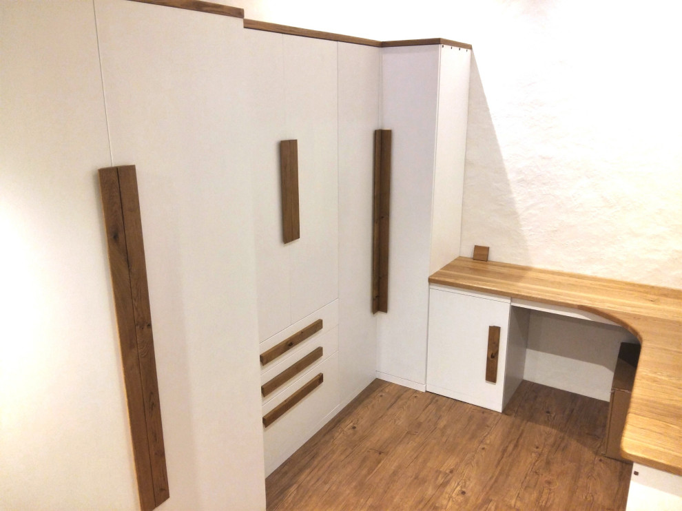Cette image montre un bureau design de taille moyenne avec un mur blanc, un sol en bois brun, un bureau intégré, un sol marron et poutres apparentes.