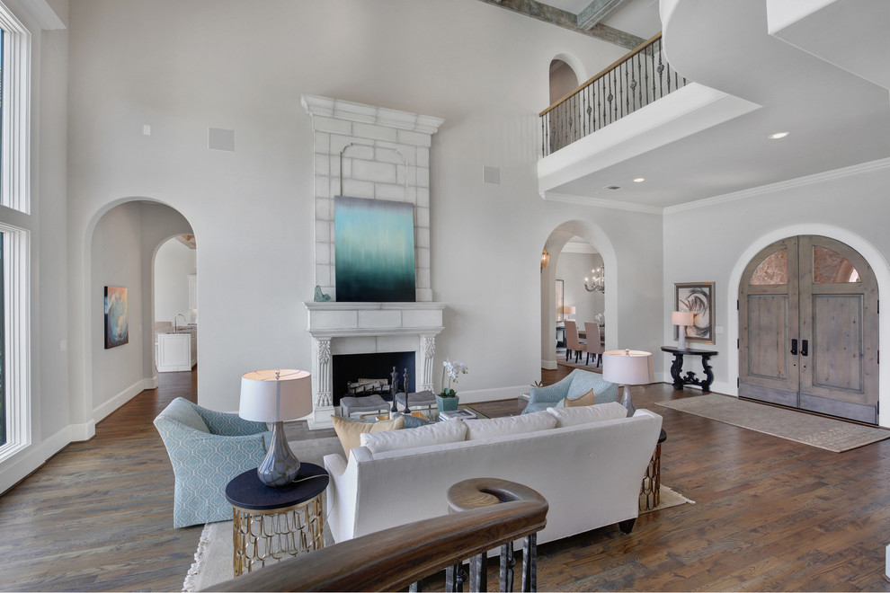 Design ideas for a large mediterranean open concept living room in Dallas with grey walls, medium hardwood floors, a standard fireplace, a stone fireplace surround and brown floor.
