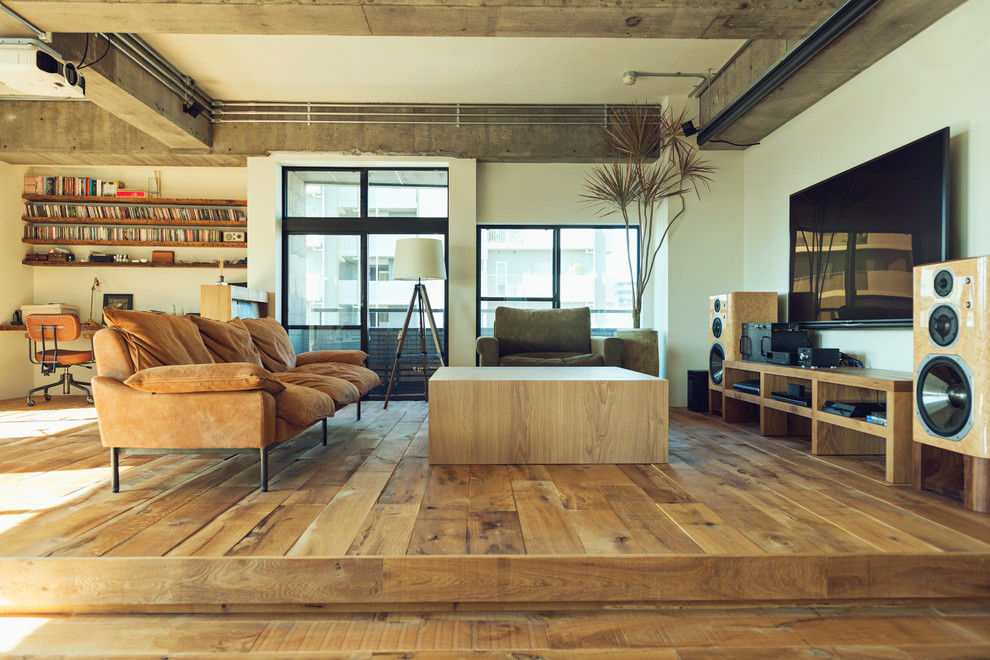 Design ideas for an industrial living room in Tokyo with white walls, medium hardwood floors, a wall-mounted tv and brown floor.