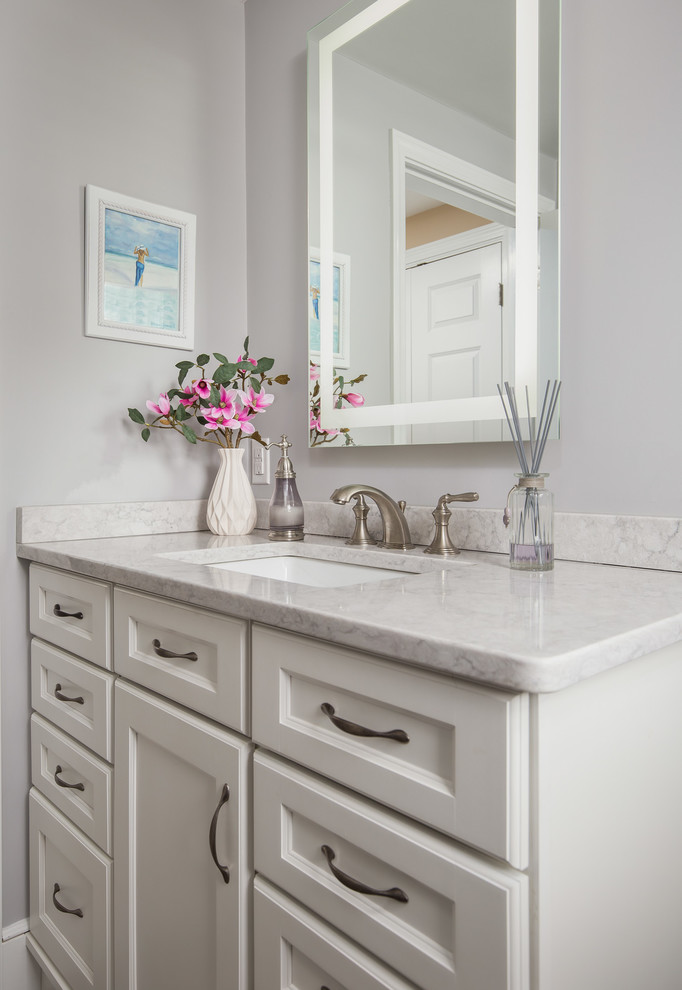 Inspiration for a mid-sized transitional master bathroom in Boston with shaker cabinets, yellow cabinets, a curbless shower, a two-piece toilet, gray tile, porcelain tile, grey walls, porcelain floors, an undermount sink, engineered quartz benchtops, grey floor and a hinged shower door.